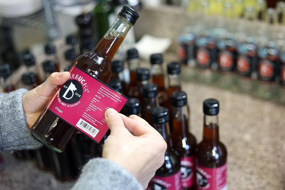 Hands labelling kombucha bottles